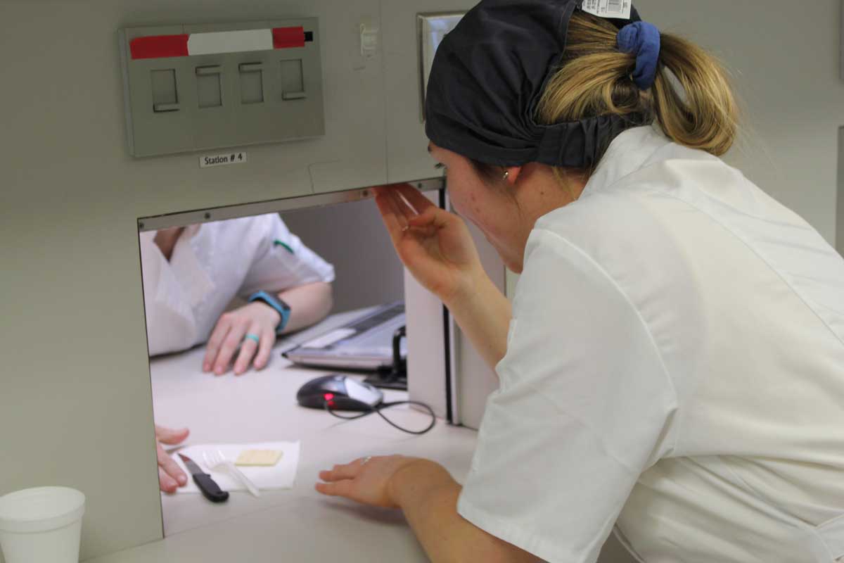Rachel Schreck in food science sensory lab giving sample to subject.