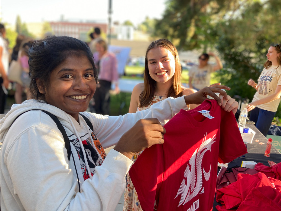 A student holds up a coug shirt, looking into whether she'll buy it.
