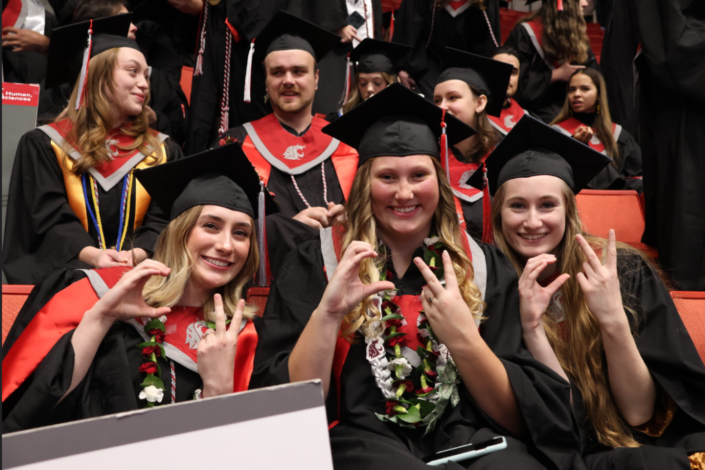 Three students hold up their hands in a shape that spells "CV".