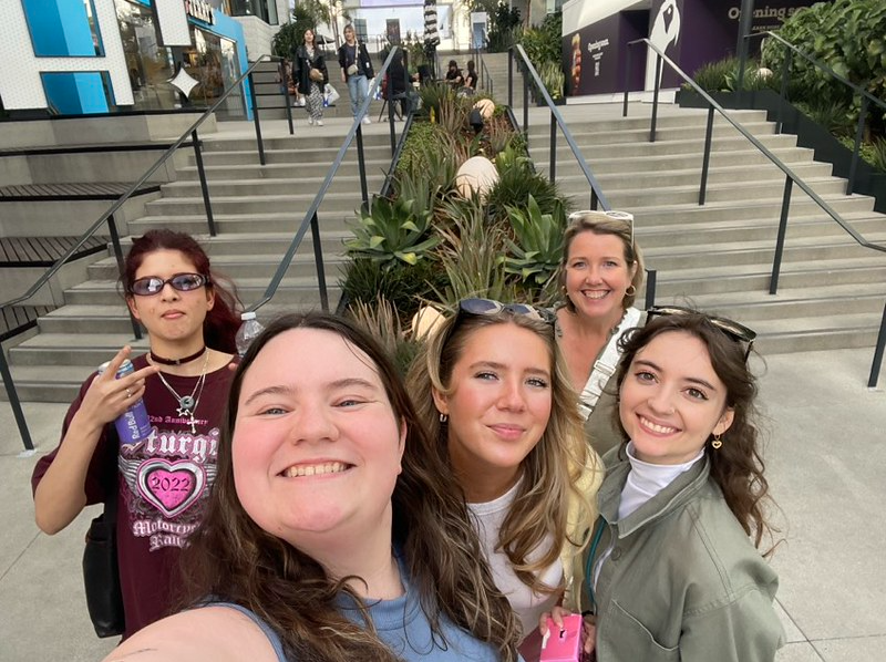 Attendees of the AMDT trip take a selfie in LA in front of a staircase of the visiting companies full of LA grassy plants, having way too much fun