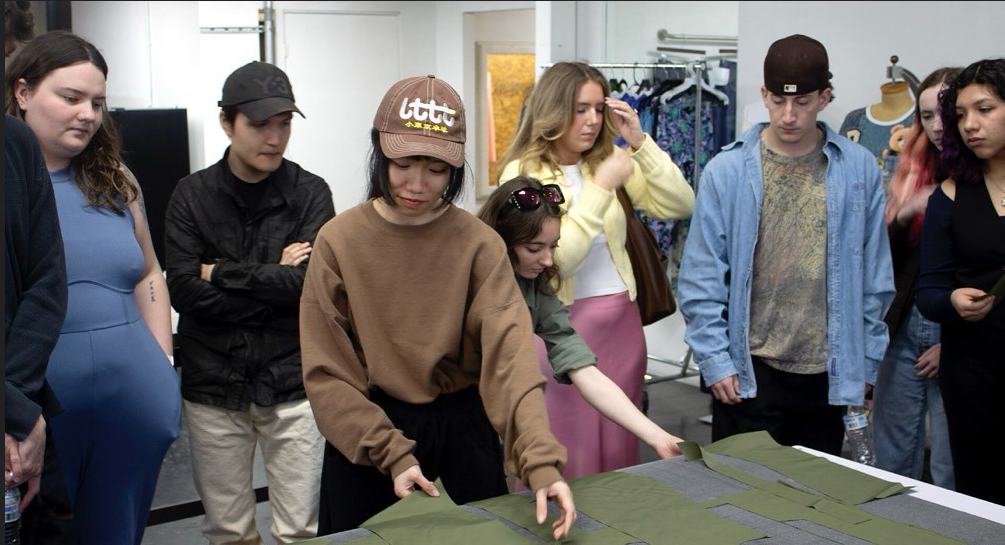 Students touching real pattern pieces that have just been cut out on the conveyer belt during an experience at Tuka Tech.