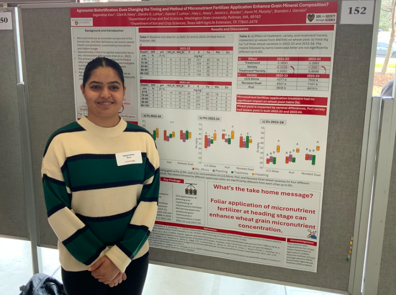 A student stands next to her posterboard with her research