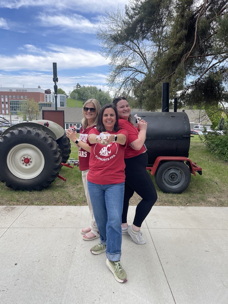 Colette, Emily, and Nancy pose like spies, but are holding CAHNRS cow keychains and smiling.
