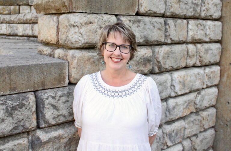 Kelli Gardner poses in front of a brick wall.