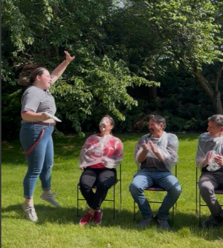 Emily Libey springing off the ground in glee after shoving a pie in  Advisor Colette Casavant's face.