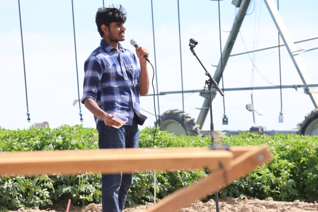 A presenter speaks with a mike in front of field day attendees