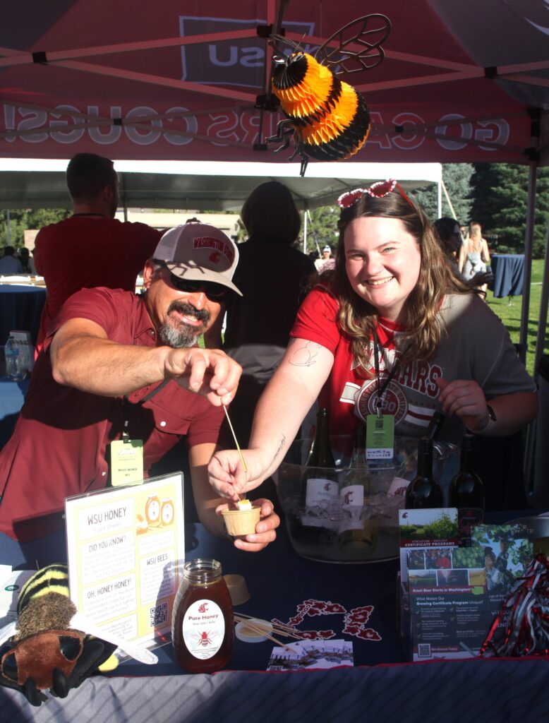 Miguel Inzunza and Emily Libey hold up samples at the CAHNRS Crave Festival booth