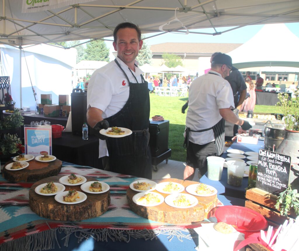 An aproned chef holds up an incredible pork dish at Crave Festival.