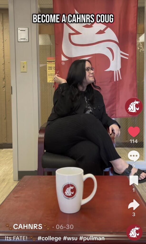 An employee holds up a pen to toss it into a mug for a tiktok challenge, with the caption reading 'become a CAHNRS coug"