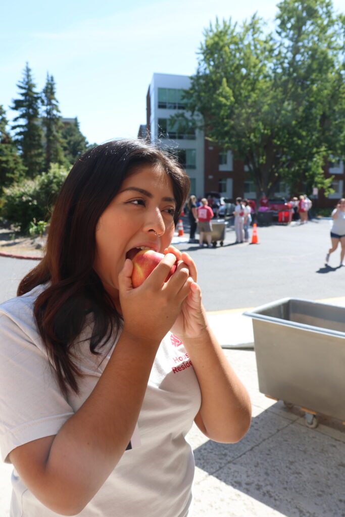 A student takes a big bite of a Cosmic Crisp at move-in weekend.