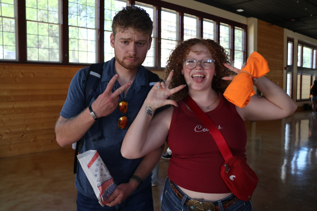 Two students give peace signs, one holding a t-shirt she won in the t-shirt toss.