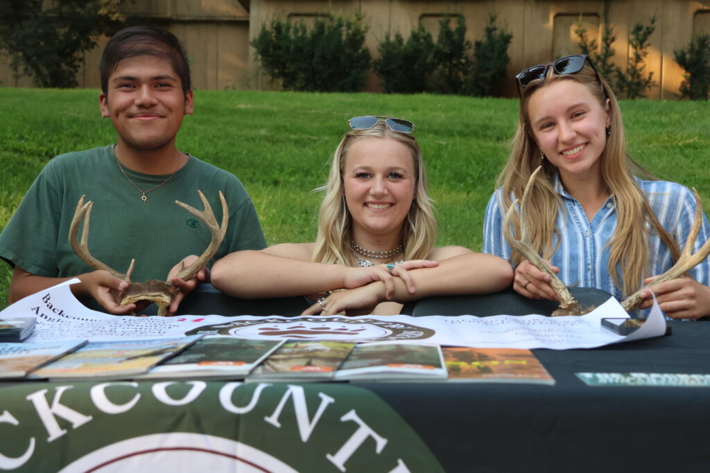 A booth at Fall Festival where booth volunteers are holding antlers