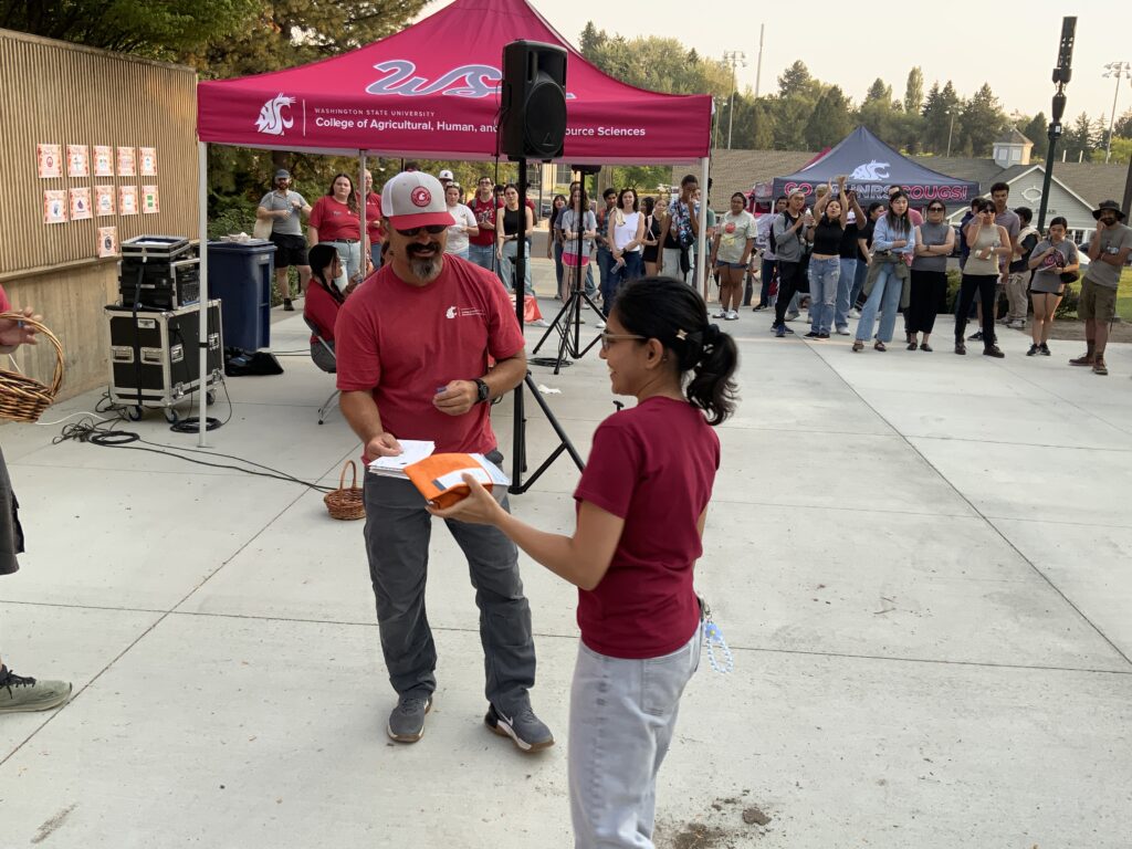 A student receives a prize, specifically a Thomas Hammer bag of coffee beans