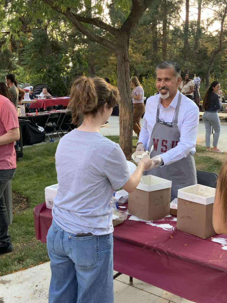 Dean Raj Khosla hands ice cream to a student at Fall Festival