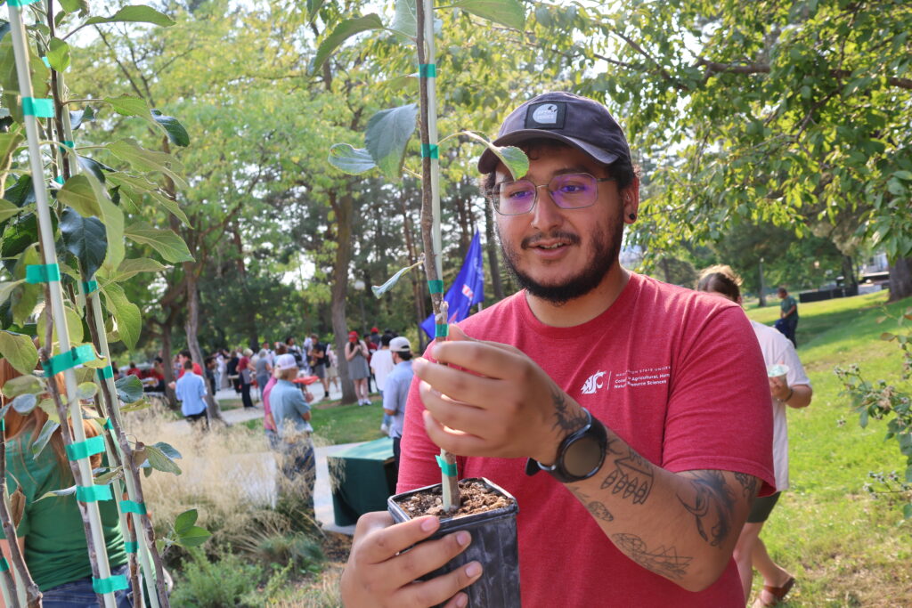 Jose Perez-Olmos holds a plant and is explaining about it to onlookers at Fall Festival 2025