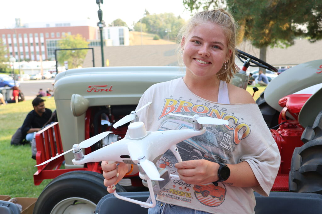 A student holds a drone in front of a tractor at Fall Festival 2025
