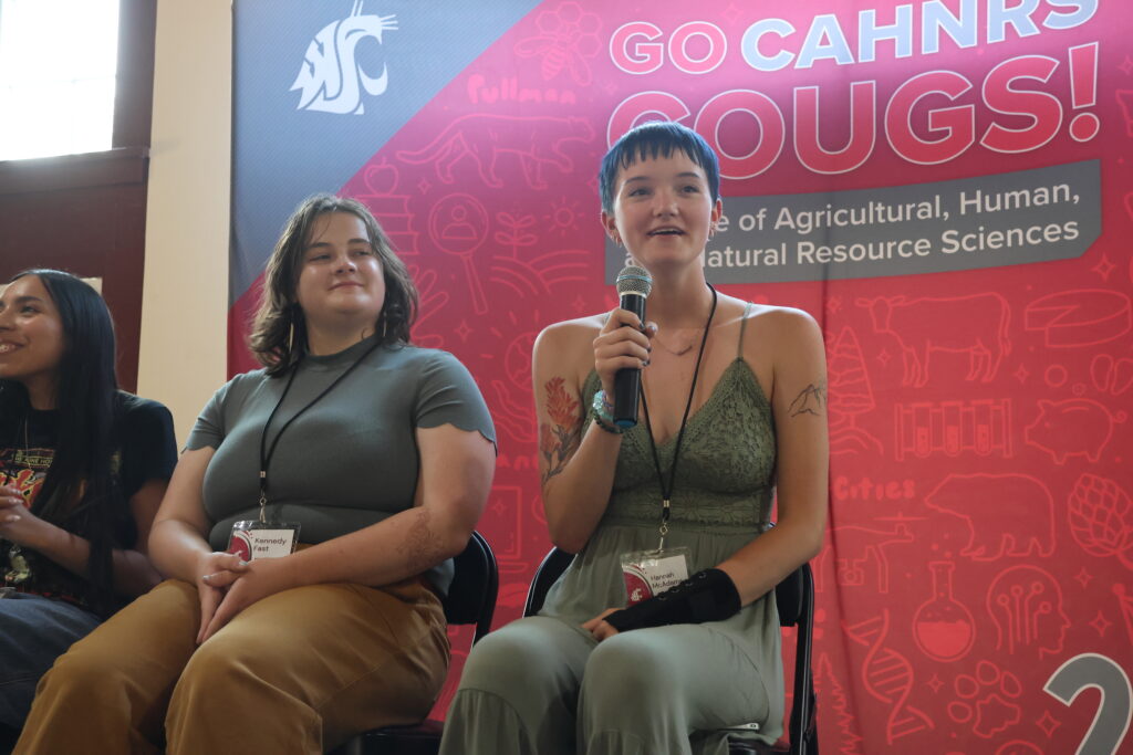 Previous top scholars sit in front of the official CAHNRS background on the stage at Orientation Dinner, giving advice to future Top Scholars