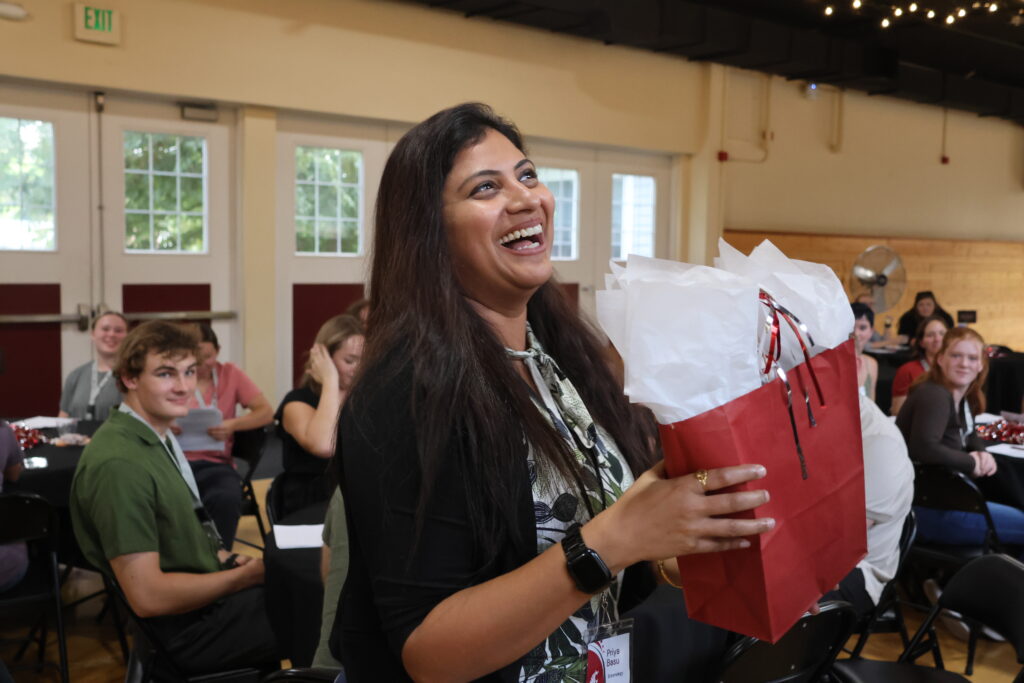 An attendee gleefully accepts a gift bag at Orientation Dinner