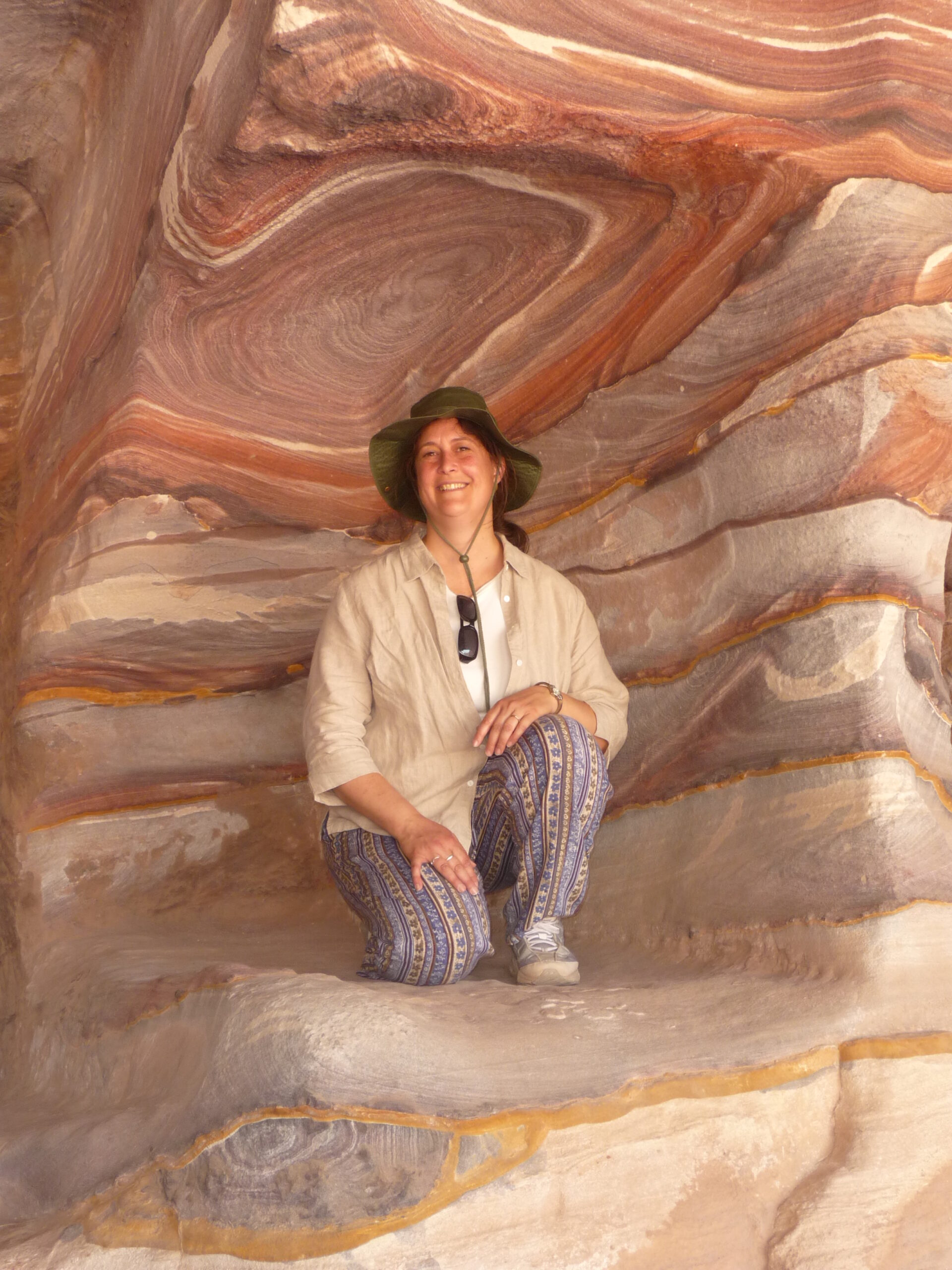 Cathy Perillo poses in a cave with layered rock swirls.