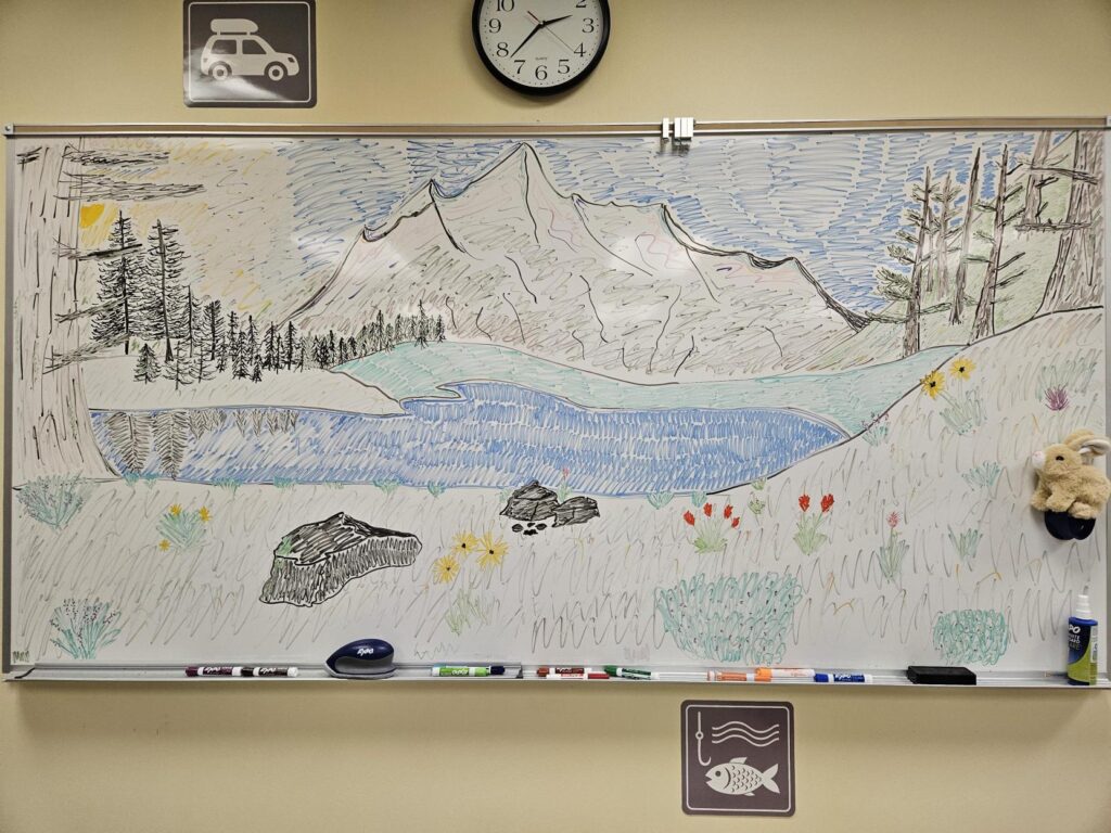 A mountain scene drawn in whiteboard marker on a large whiteboard