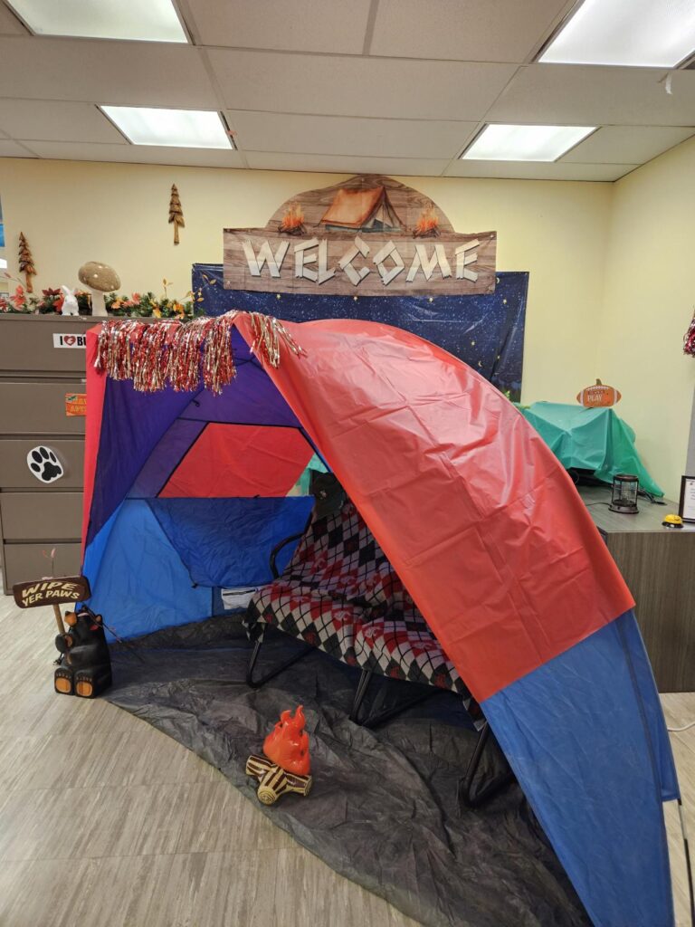 A tent with an official argyle Cougars print blanket on a couch, with a mini fake fire