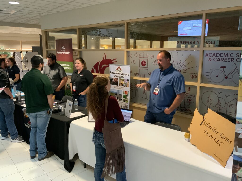 a Schneider Farms representative talks with a student at his Career Fair booth