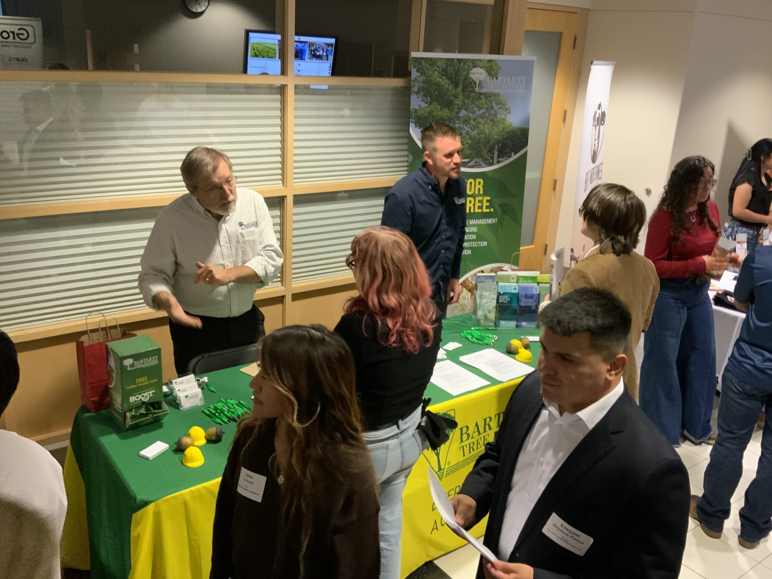 A group of students visit an employer booth at the 2025 fall networking night event in Lighty Student Services, discussing their business and learning more about internships and job opportunities.