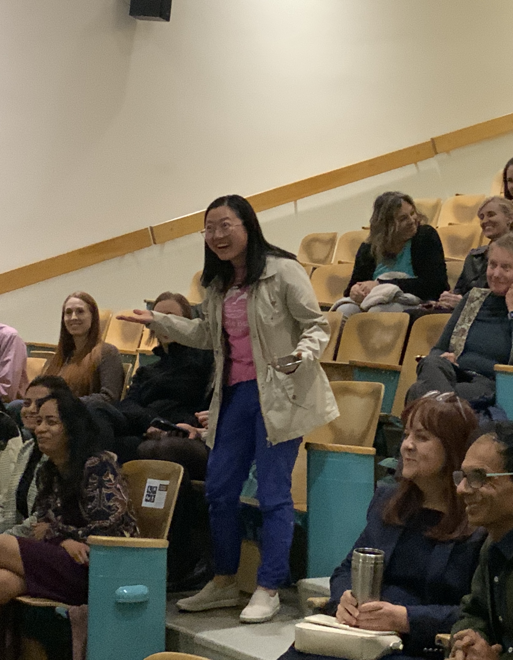 A faculty member asks a question enthusiastically to the dean and associate deans at the All-CAHNRS Meeting in 2025, part of a crowd made up of CAHNRS employees.