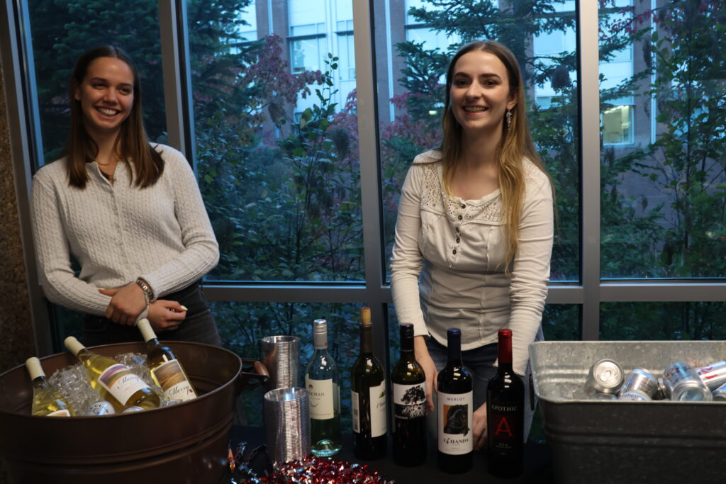 Elizabeth and Siari work behind a table of drinks at the All CAHNRS Meeting reception table.