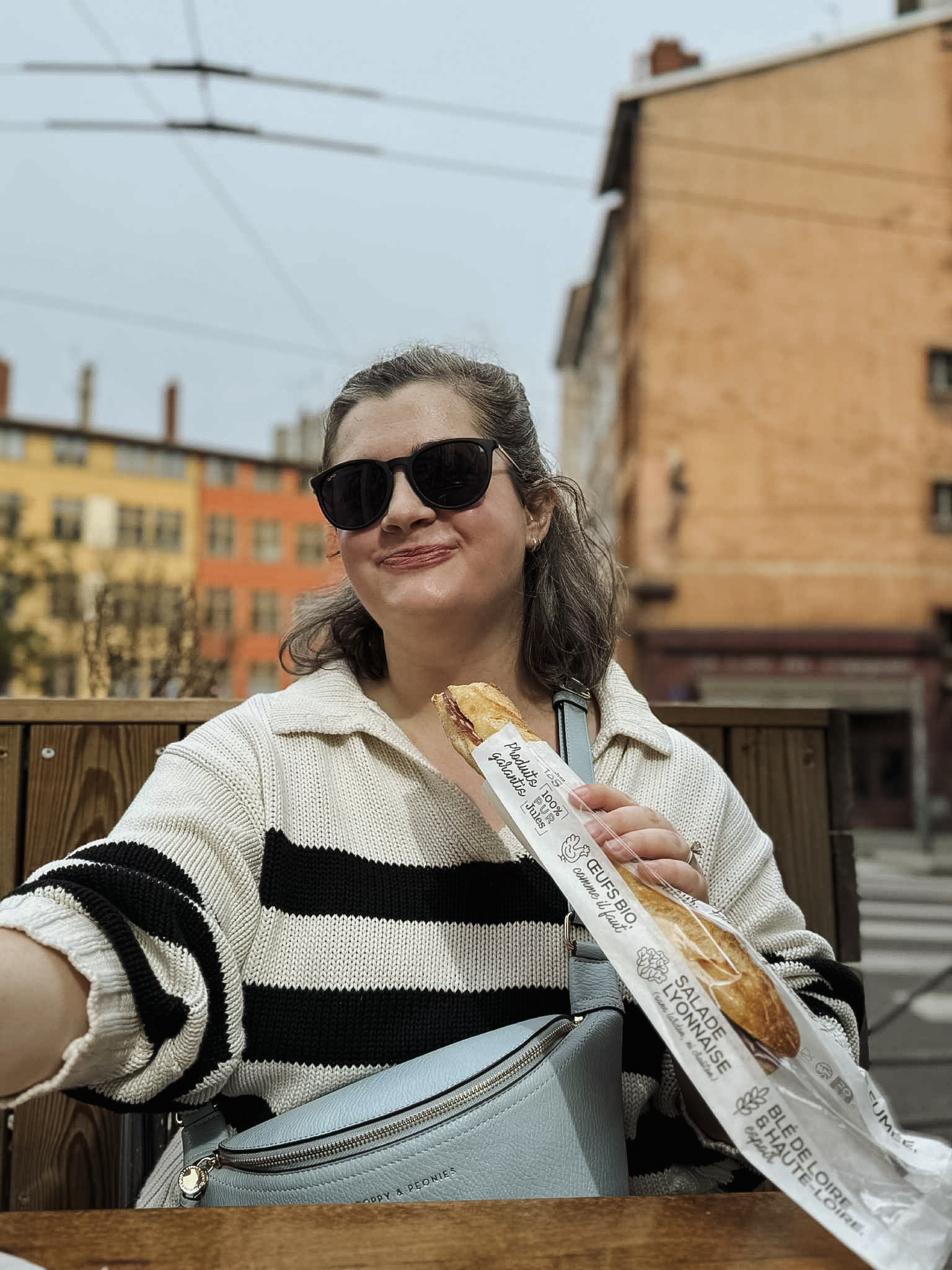 Emma Pesis eats a baguette in a city environment.
