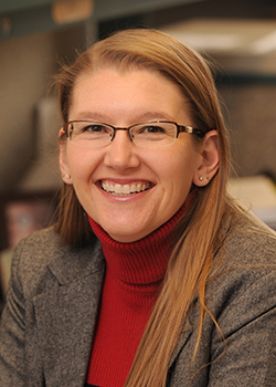 Lisa Hunter close-up of her smiling in a crimson turtleneck and blazer.