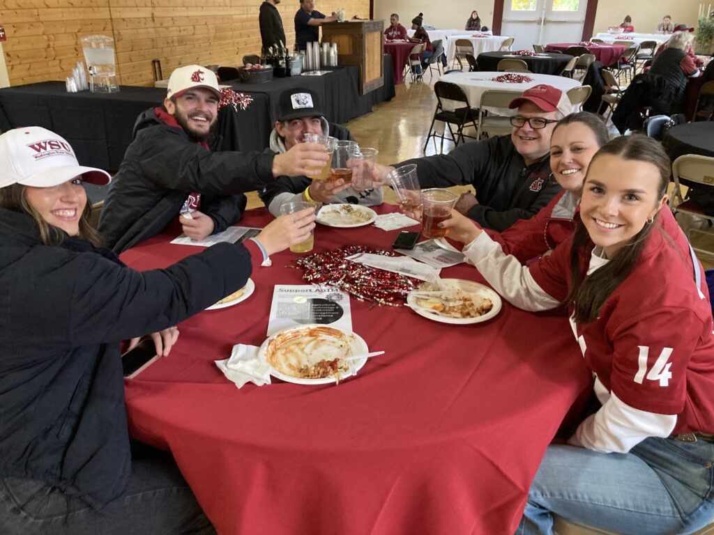 Attendees of Beef & Brews clink glasses of beermosa in a gesture of cheers, smiling widely at the fun day just beginning.