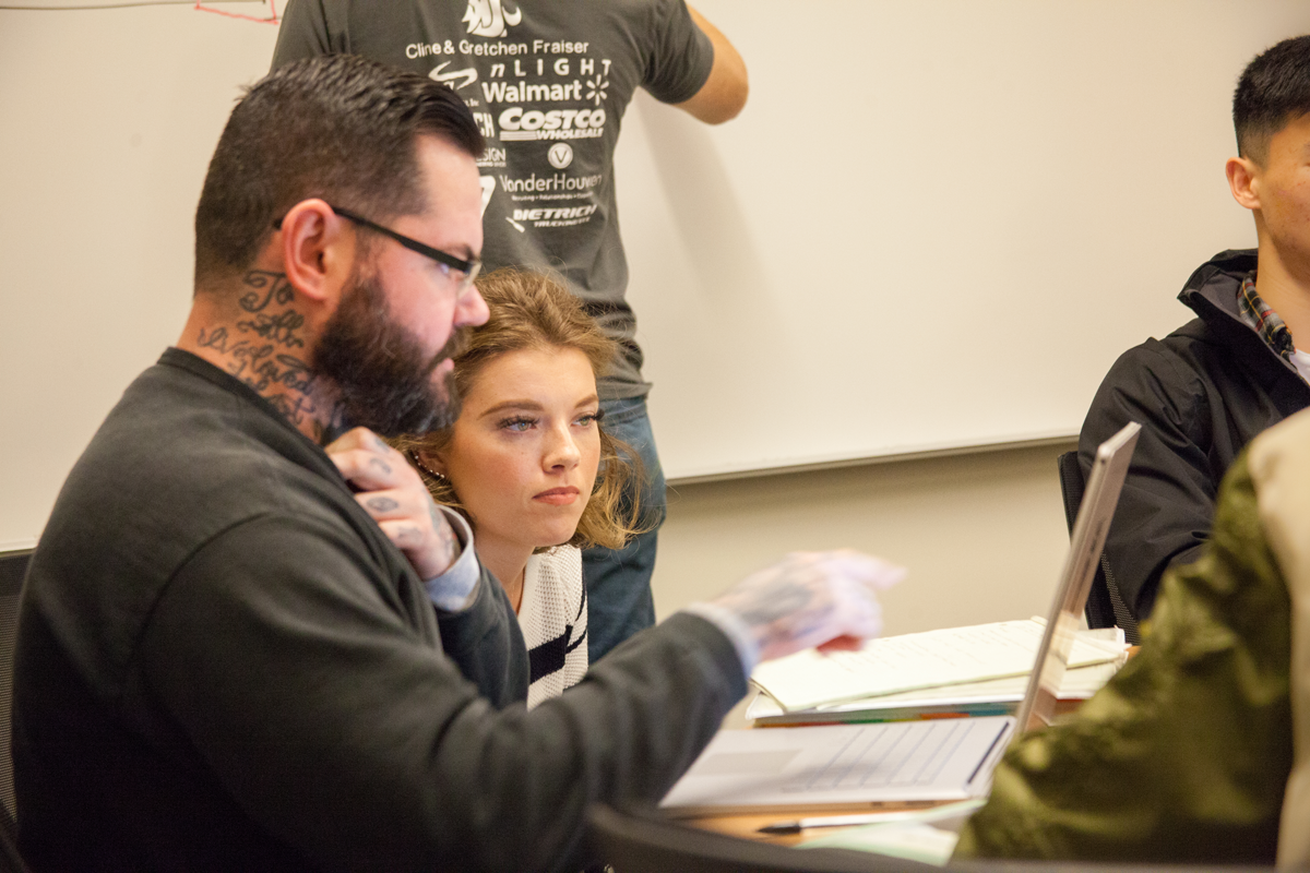 A student intently listening to a professor, as they go over correct answers on paper