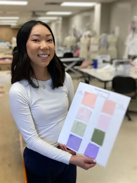 College student holding colorful fabric samples in a binder