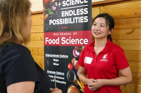A food science graduate student tabling at a recruitment event with a Food Science sign behind them