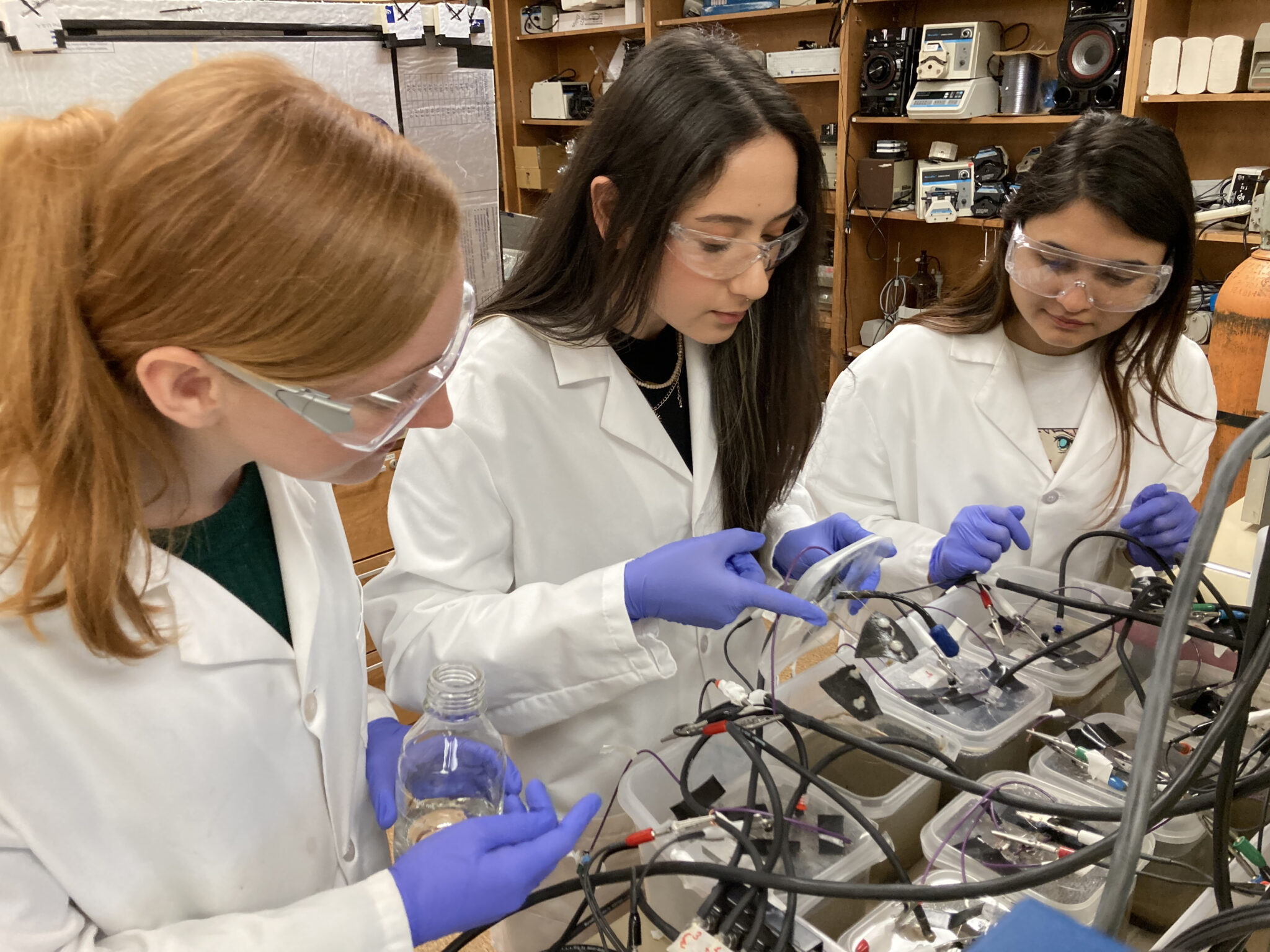 A group of three students working together on a machine that analyzes plant pathogens