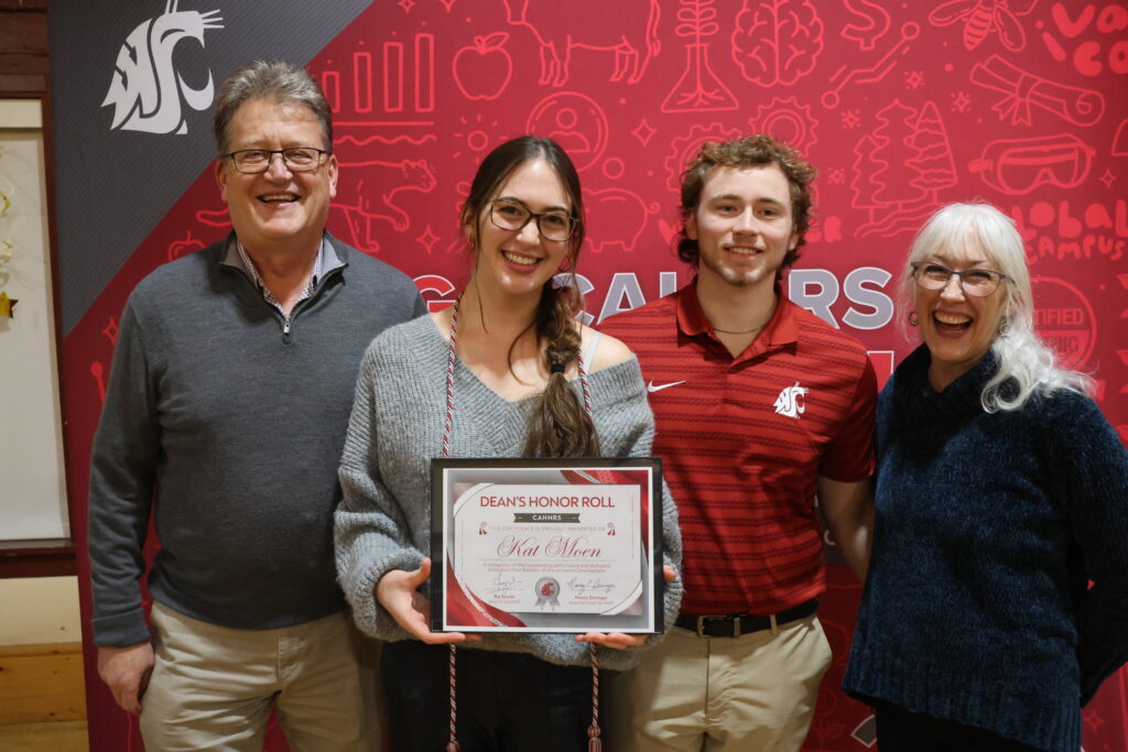 A Dean's Honor Roll student, Kat Moen, poses with her family while wearing her honor cord and holding her certificate.