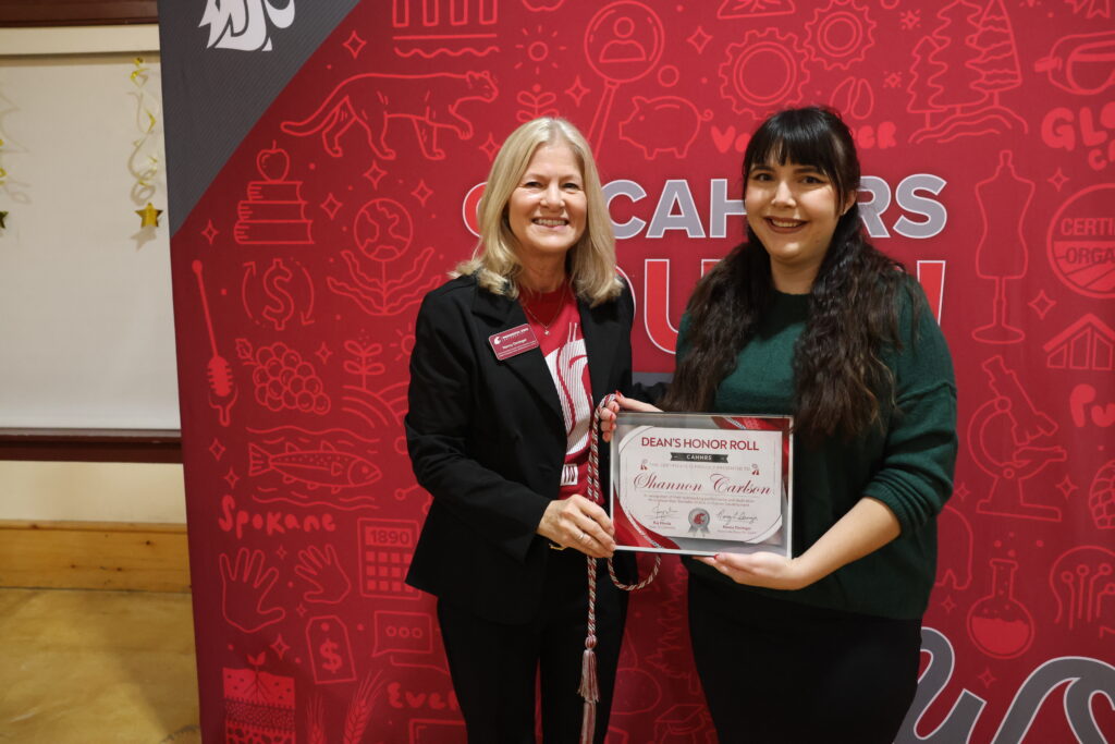 Nancy Deringer hands a Dean's Honor Roll student a certificate.