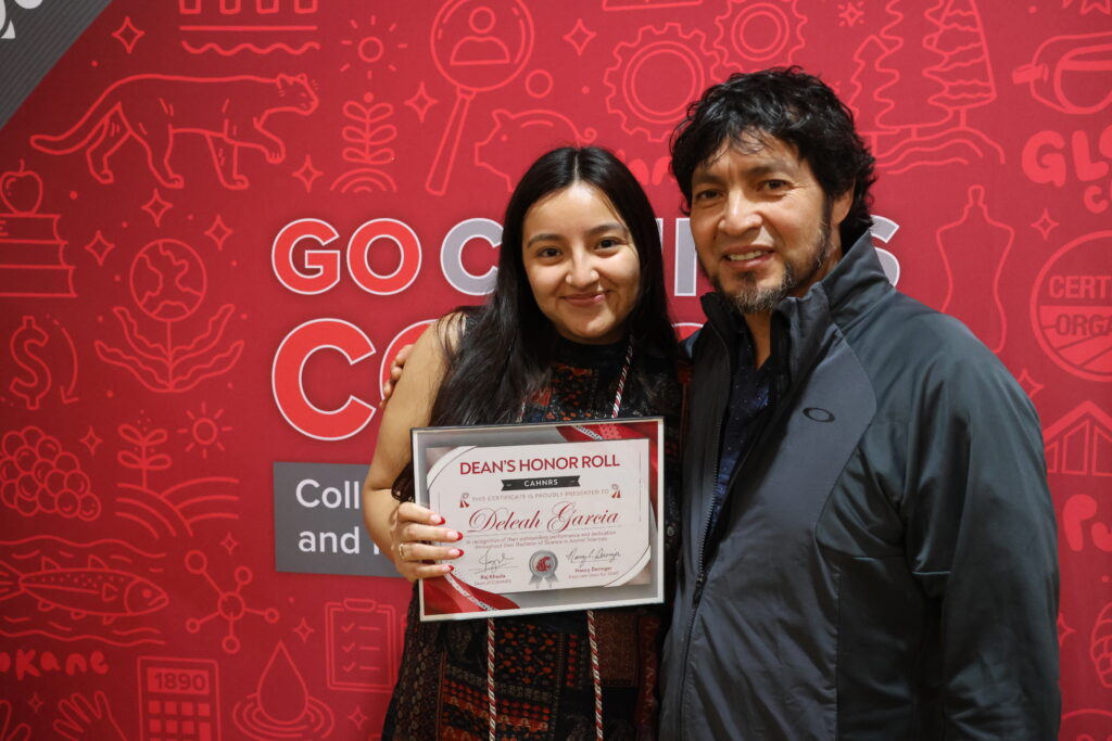 A student, Deleah Garcia, poses with her family member while holding her Dean's Honor Roll certificate.