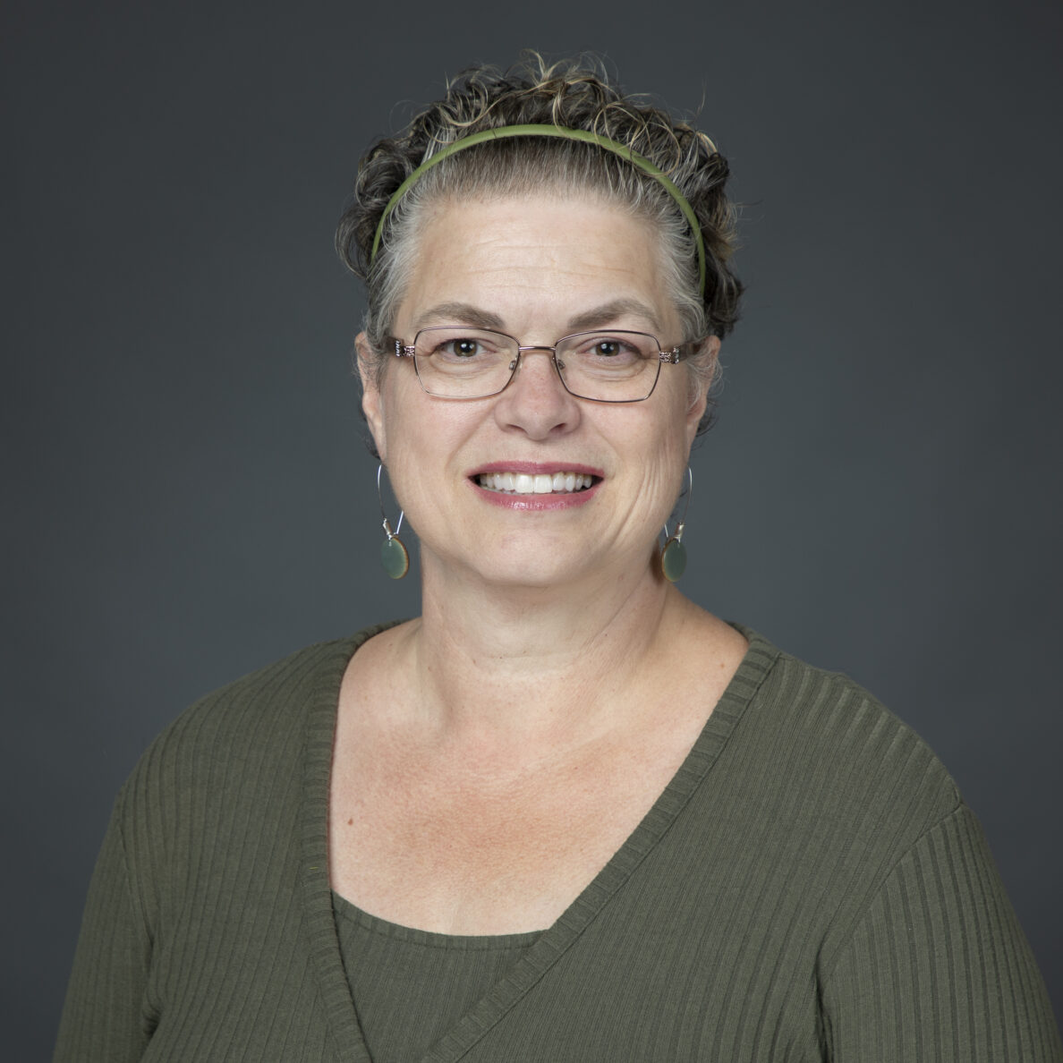 Headshot of Kat Odell in glasses, headband, and a green blouse, smiling.