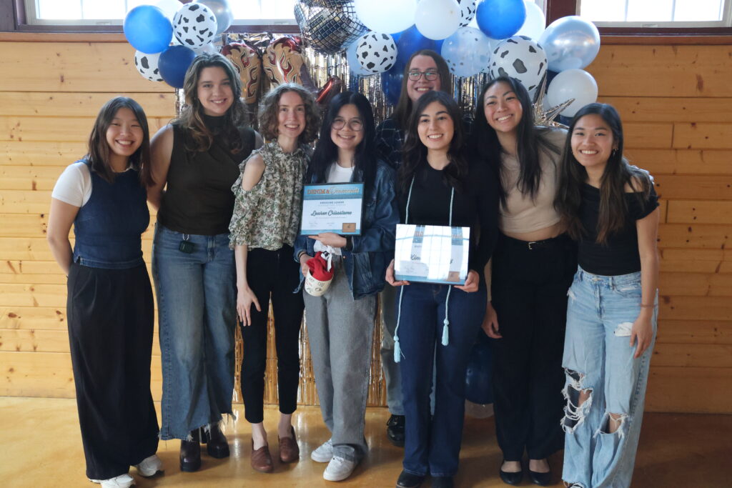 A group of students pose with their awards in front of a western-themed background at Student Awards.