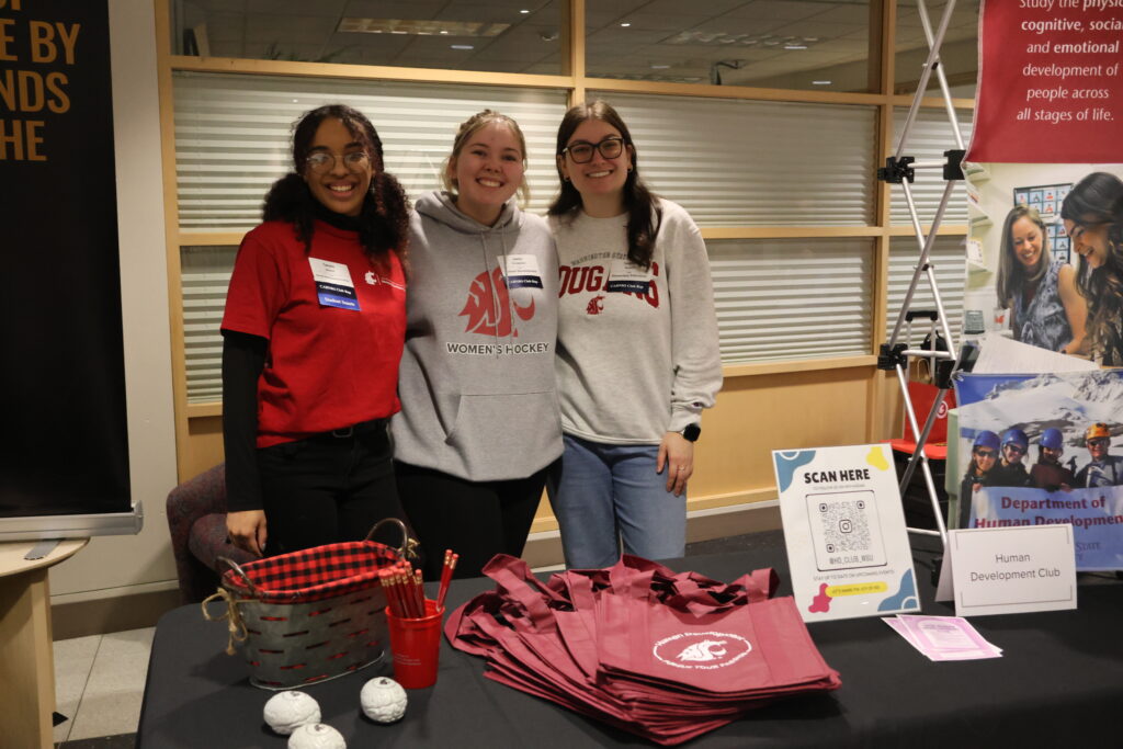 Three students pose with WSU themed bags and other goodies up for grabs at their booth at the CAHNRS Career Fair and Networking Night.