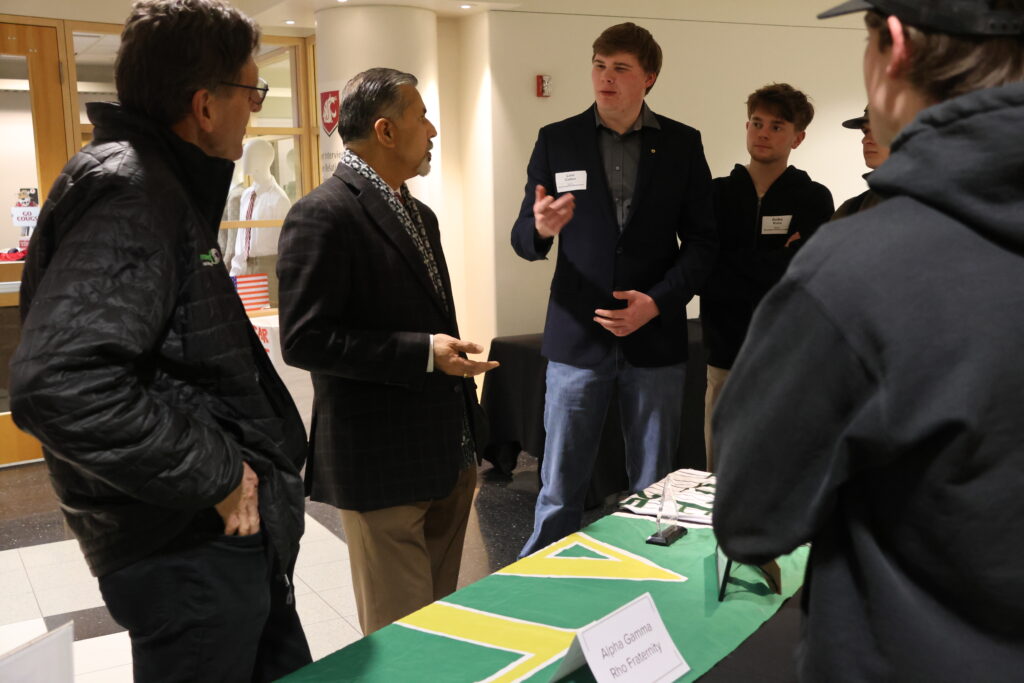 Dean Khosla and Associate Dean Hulbert engage in conversation with student members of the Alpha Sigma fraternity booth at the CAHNRS Career Fair and Networking Night.
