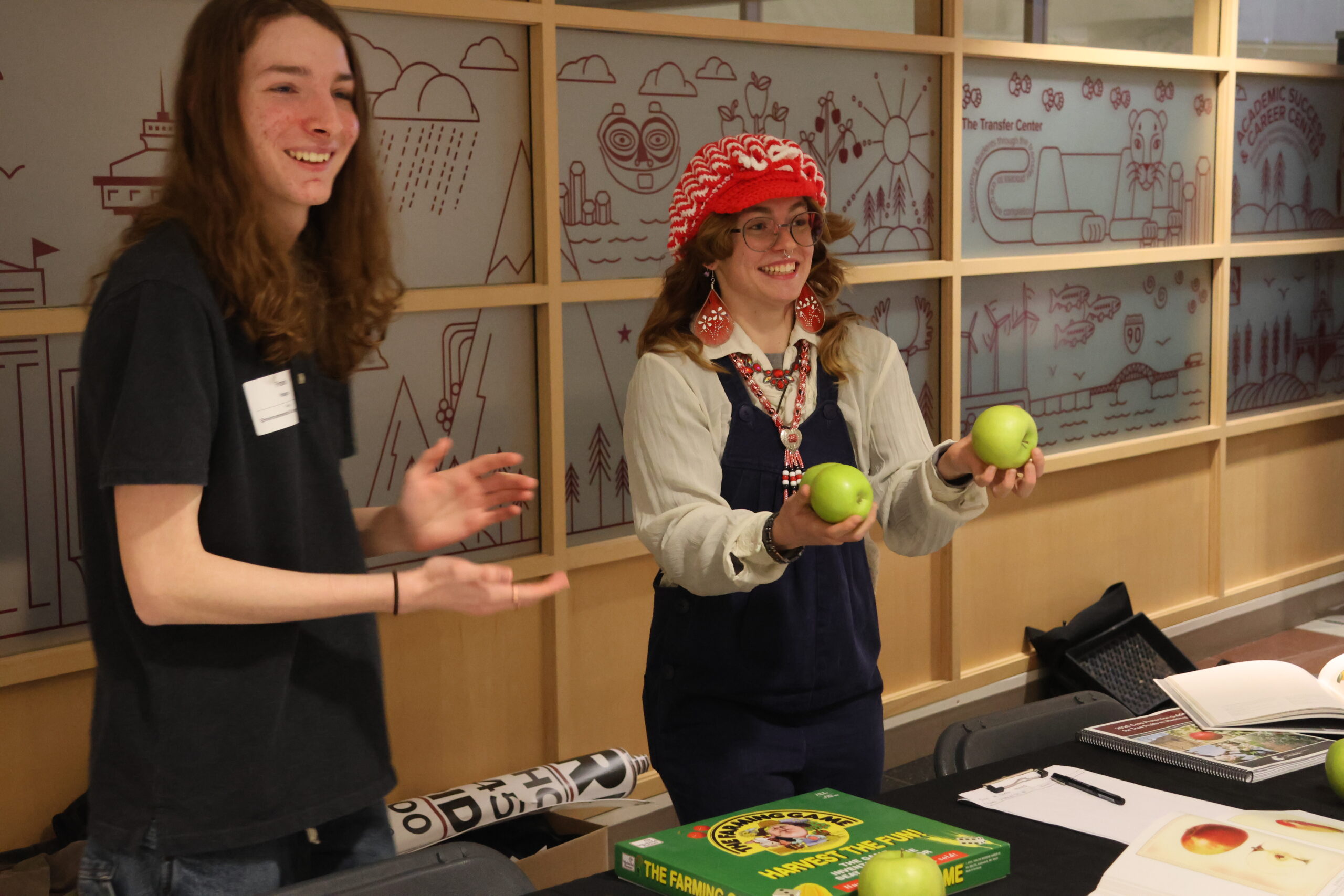 A student member of the HORTA club waves around some green apples, talking to a student attendee at the CAHNRS Career Fair and Networking Night.