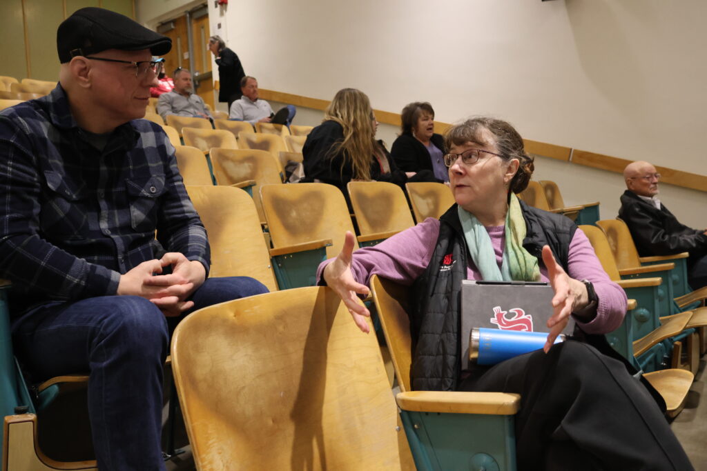 Two attendees to the CAHNRS Town Hall discuss in the audience before the event starts.