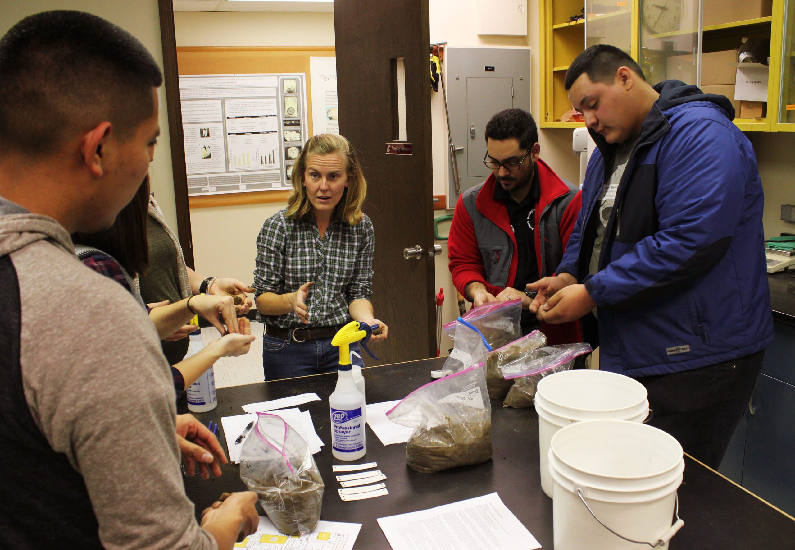 A professor explains to students in a hands-on lab experience, supplies and materials in their hands.