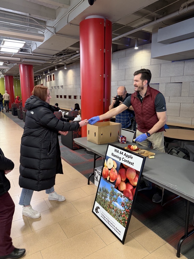 A former employee in CAHNRS takes a first taste of the Sunflare apple from Jeremy Tamsen, Director of the Office of Commercialization at WSU.