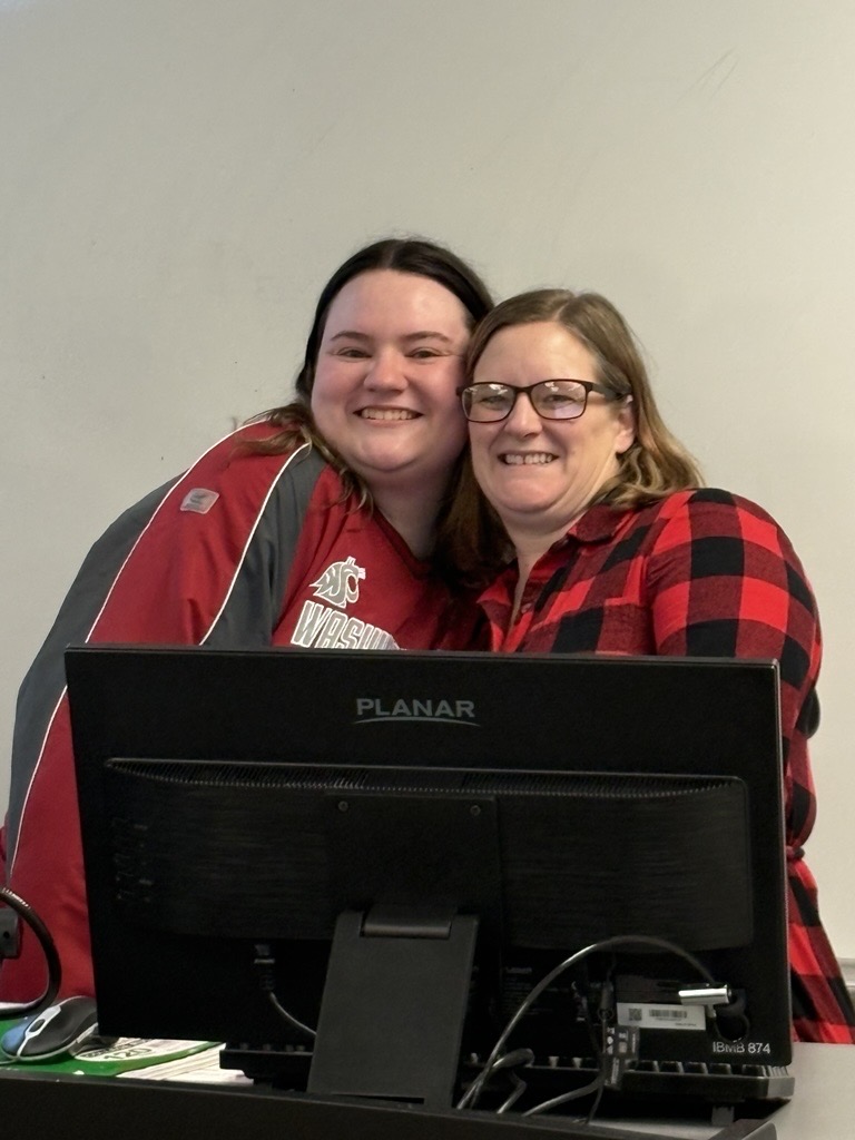 Two CAHNRS Cougs are behind a computer looking happy.