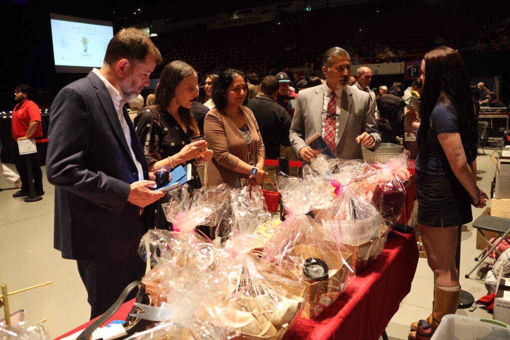 Attendees at the fashion show, including Dean Khosla, browsing silent auction items.