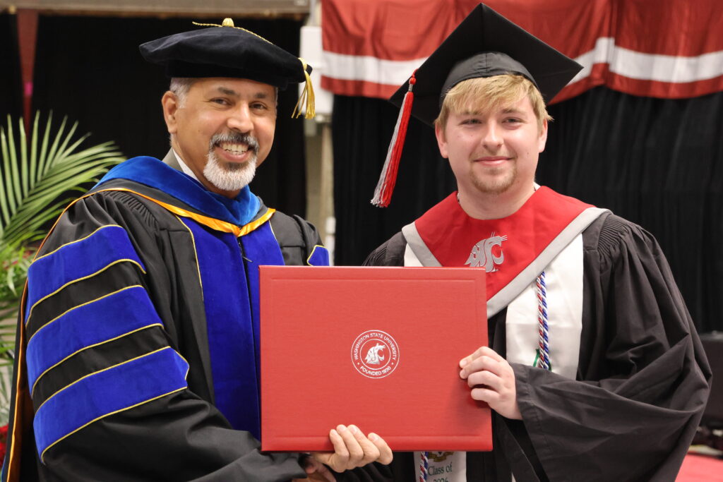 Dean Khosla handing a degree to WSU graduate.